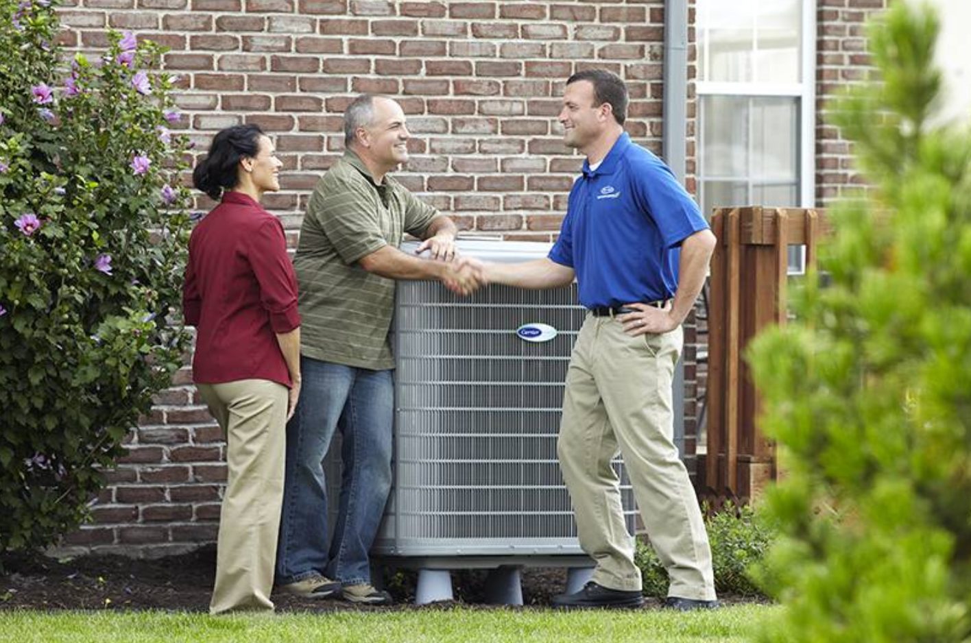 A couple and an HVAC technician discussing their heat pump in New Lenox, IL